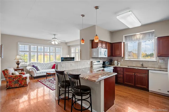 a open kitchen with stainless steel appliances granite countertop wooden cabinets a dining table and chairs