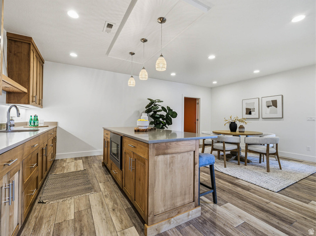 402 Shadow Hill Road Wanship, UT 84017 - Photo 45 of 90 Kitchen with a center island, light wood-style flooring, wood finish cabinets, decorative light fixtures, and a breakfast bar area