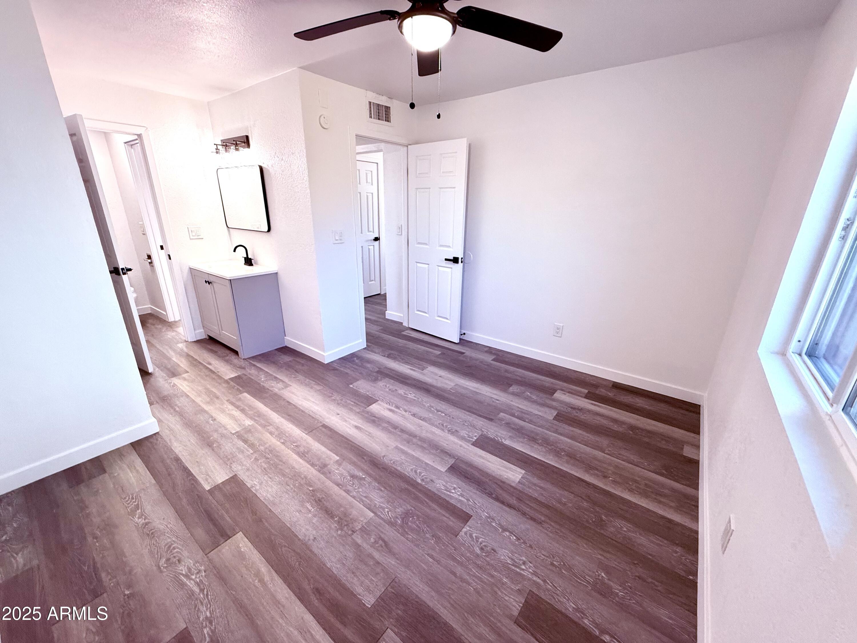 1009 East Chipman Road Phoenix, AZ 85040 - Photo 13 of 30 a view of an empty room with wooden floor and a ceiling fan