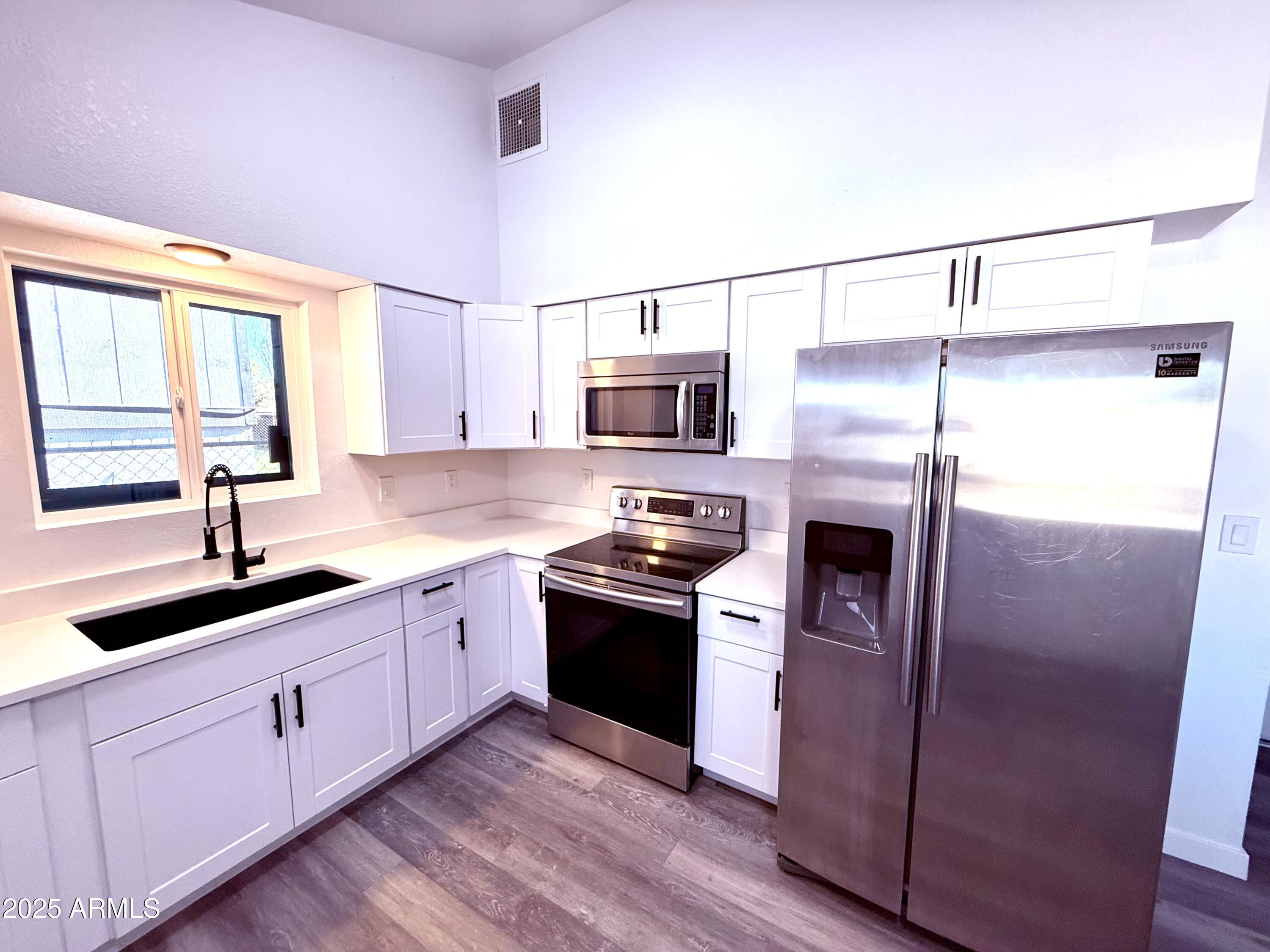 1009 East Chipman Road Phoenix, AZ 85040 - Photo 2 of 30 a kitchen with stainless steel appliances granite countertop a sink a stove a refrigerator and island with wooden floor