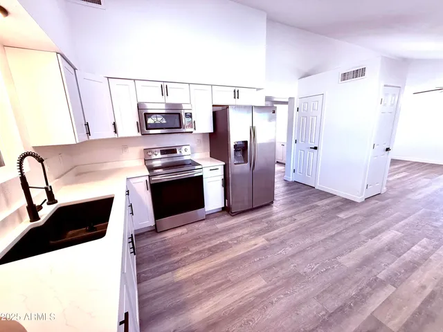 a kitchen with stainless steel appliances kitchen island granite countertop a refrigerator and a stove top oven