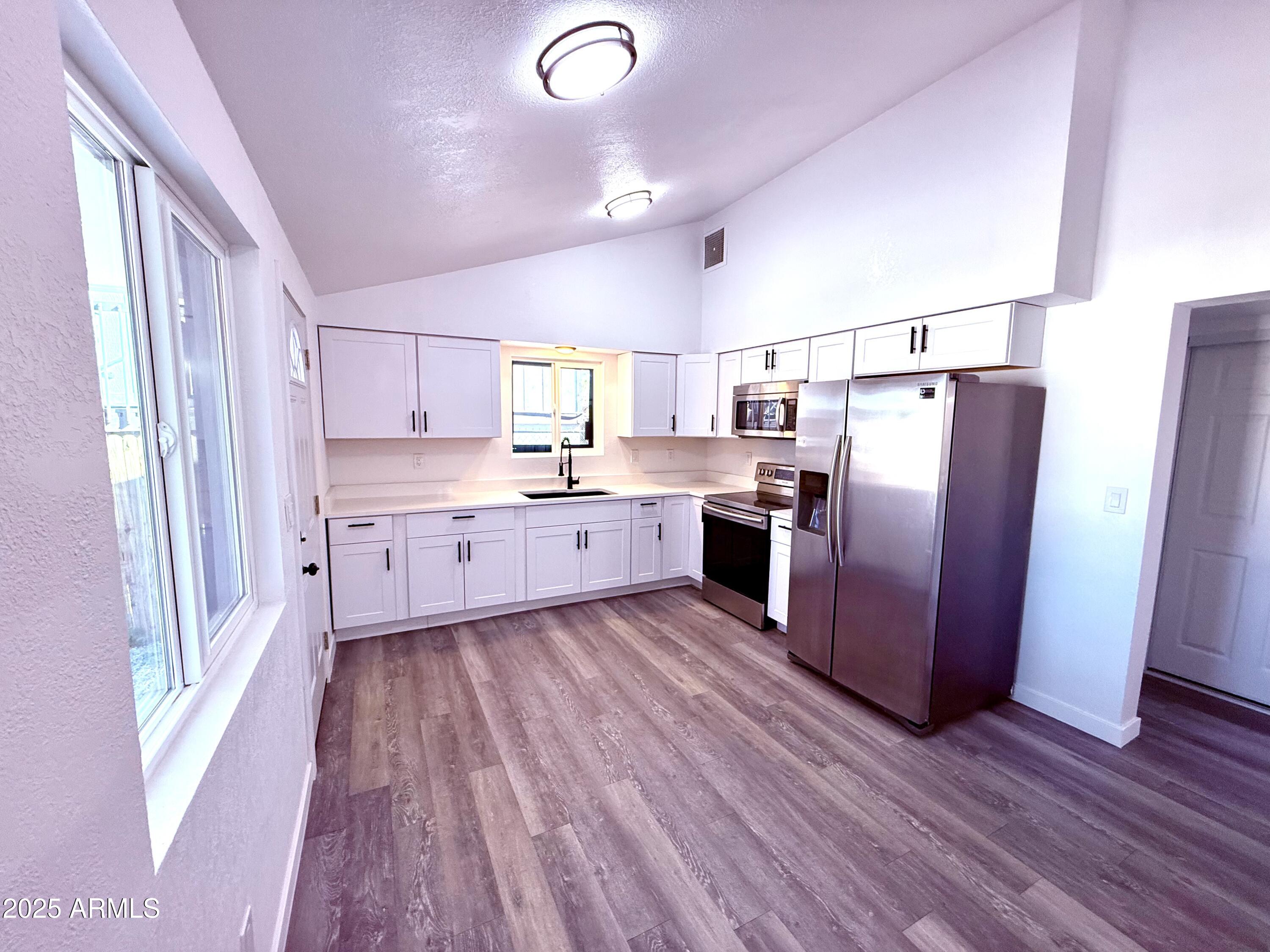 1009 East Chipman Road Phoenix, AZ 85040 - Photo 7 of 30 a kitchen with stainless steel appliances granite countertop a refrigerator a sink dishwasher a stove and white countertops with wooden floor