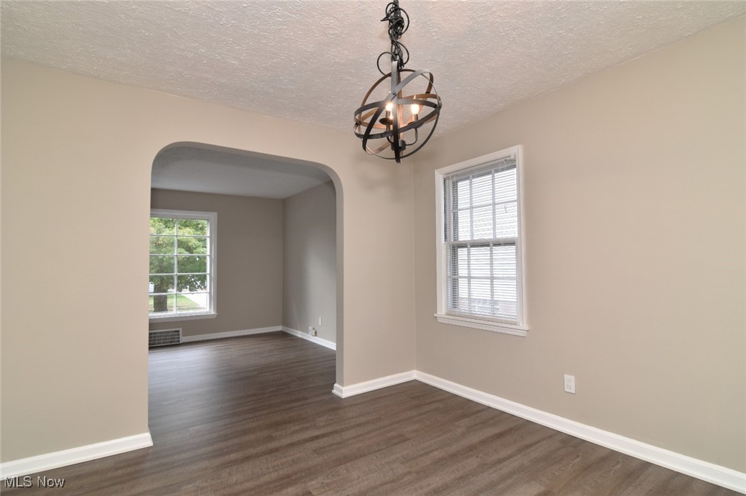 1443 Churchill Road Lyndhurst, OH 44124 - Photo 8 of 39 Empty room featuring arched walkways, dark wood finished floors, plenty of natural light, and a textured ceiling