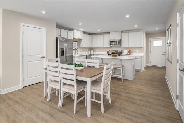 a kitchen with a dining table chairs wooden floor cabinets and stainless steel appliances
