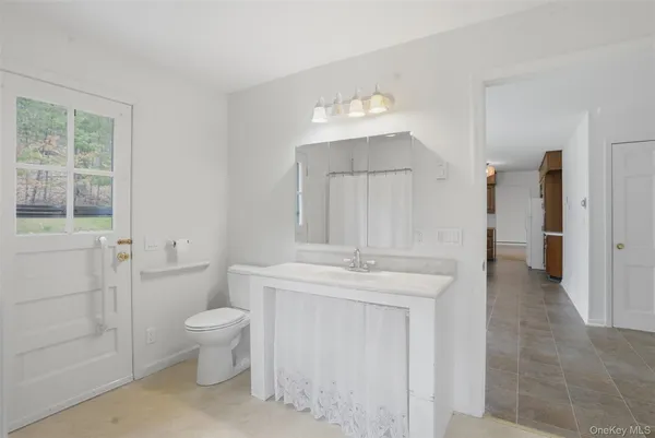 a spacious bathroom with a granite countertop sink a toilet and a mirror