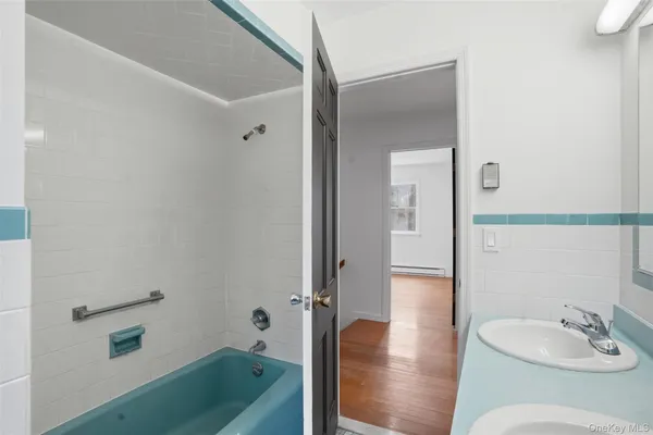 a bathroom with a tub a sink and mirror