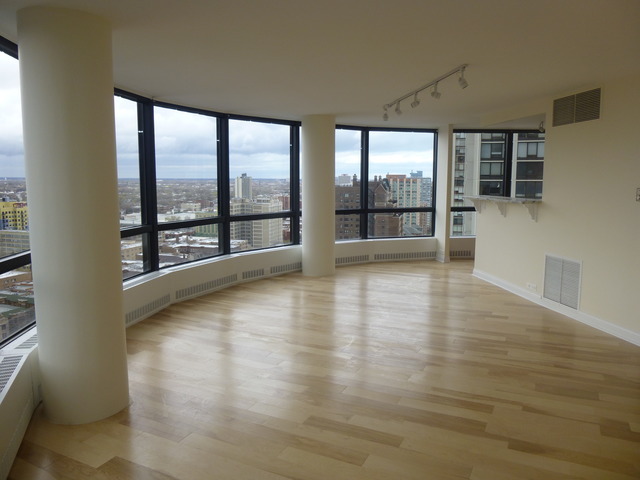 5415 North Sheridan Road, Unit 2311 Chicago, IL 60640 - Photo 3 of 18 an empty room with wooden floor and windows