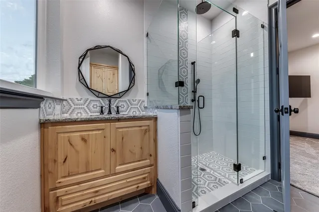 a bathroom with a granite countertop sink a mirror and shower