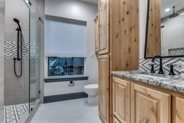 a bathroom with a granite countertop sink a toilet and shower
