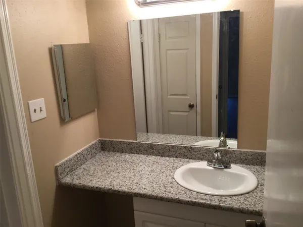 a bathroom with a granite countertop sink and a mirror