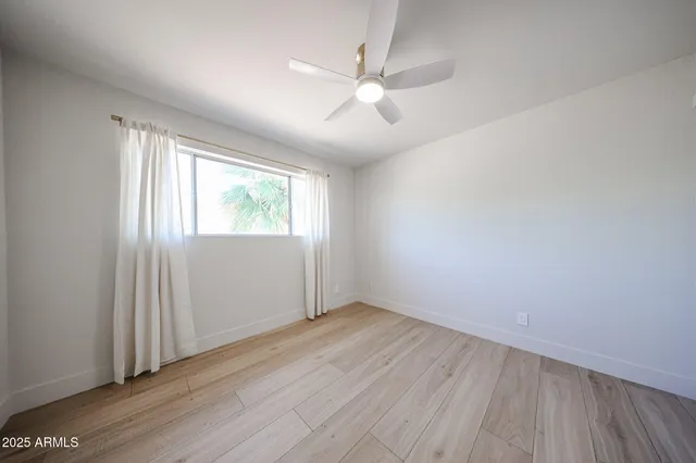 an empty room with wooden floor fan and windows
