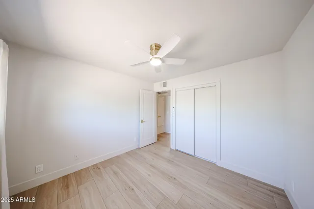 a view of a room with wooden floor and a ceiling fan