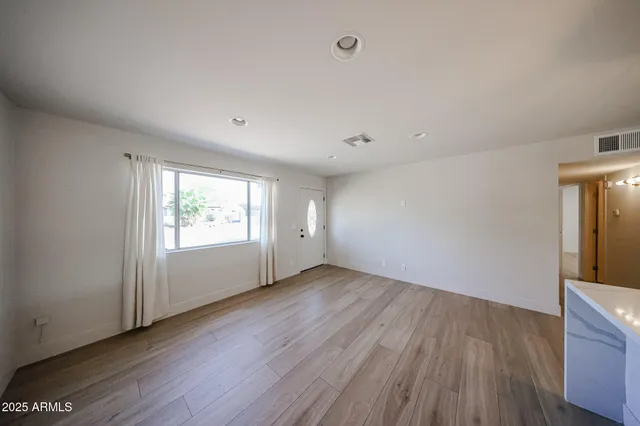an empty room with wooden floor and windows