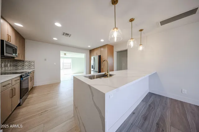 a large kitchen with kitchen island a sink dishwasher a stove and a wooden floor