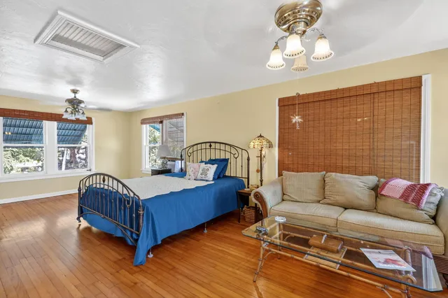an empty room with wooden floor fan and windows