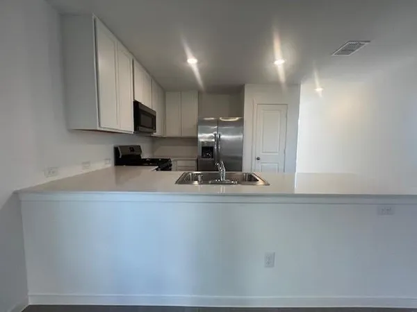 a kitchen with kitchen island a sink a stove a microwave and cabinets