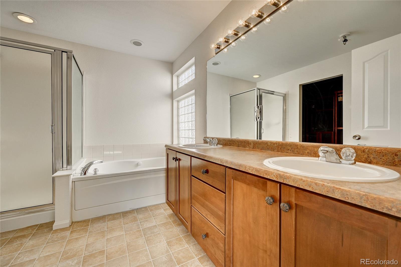 20527 Robins Drive Denver, CO 80249 - Photo 17 of 25 a spacious bathroom with a tub double sink and mirror