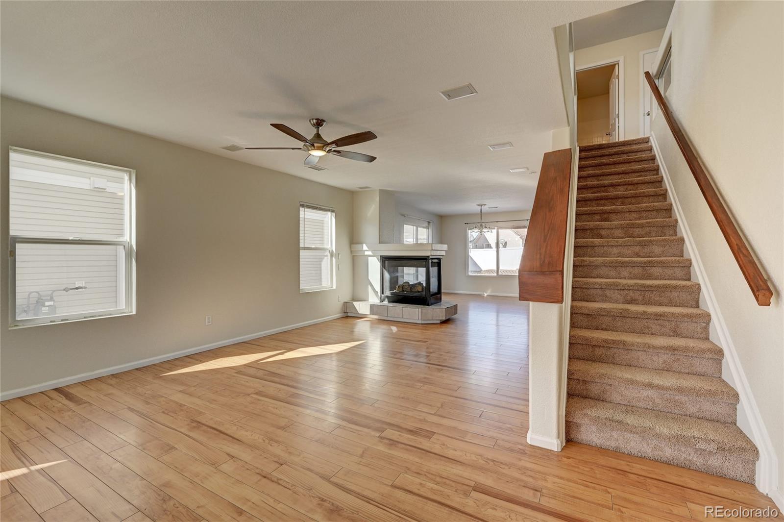 20527 Robins Drive Denver, CO 80249 - Photo 6 of 25 a view of an empty room with wooden floor a ceiling fan and windows