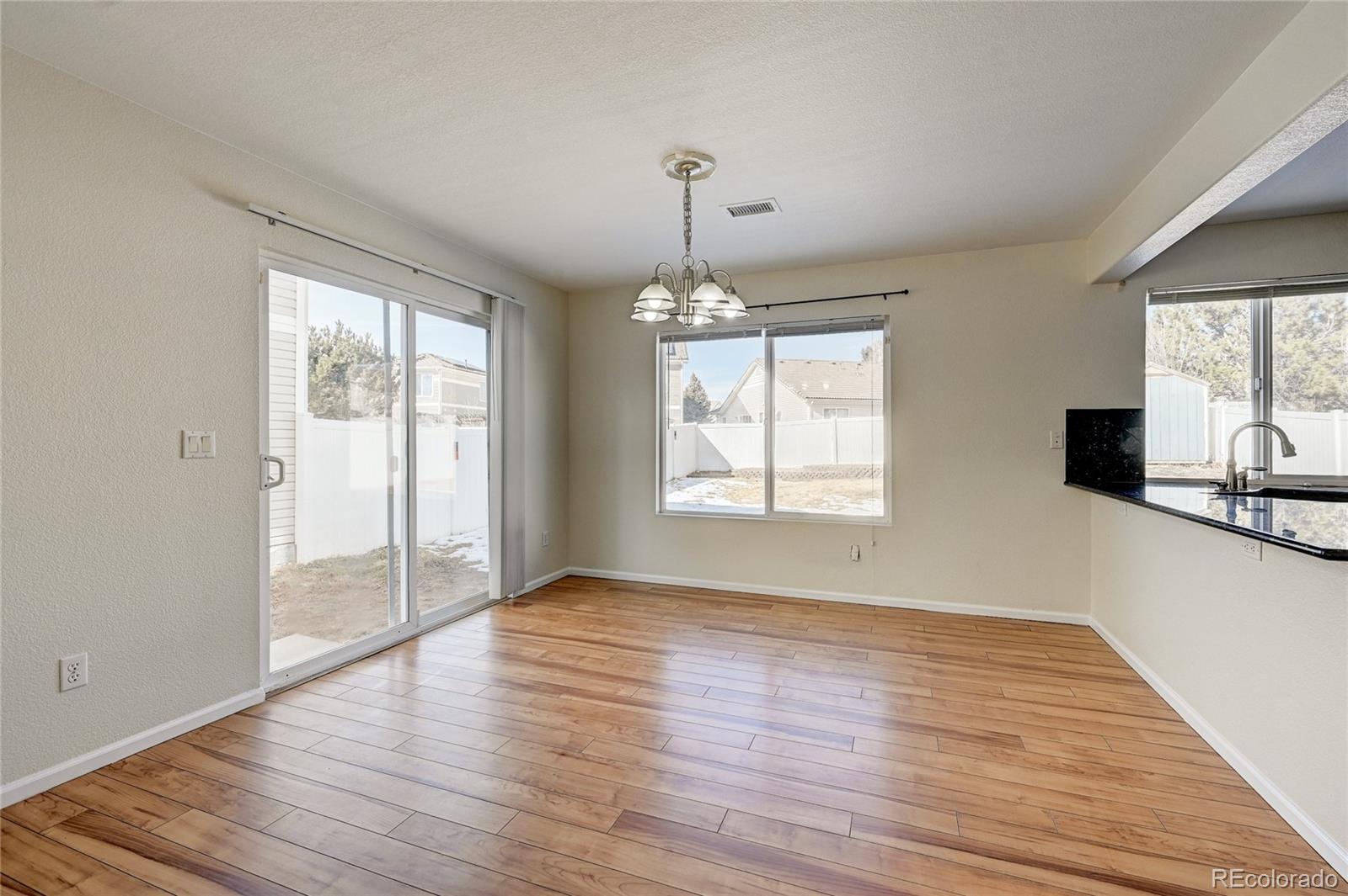 20527 Robins Drive Denver, CO 80249 - Photo 8 of 25 an empty room with wooden floor and windows