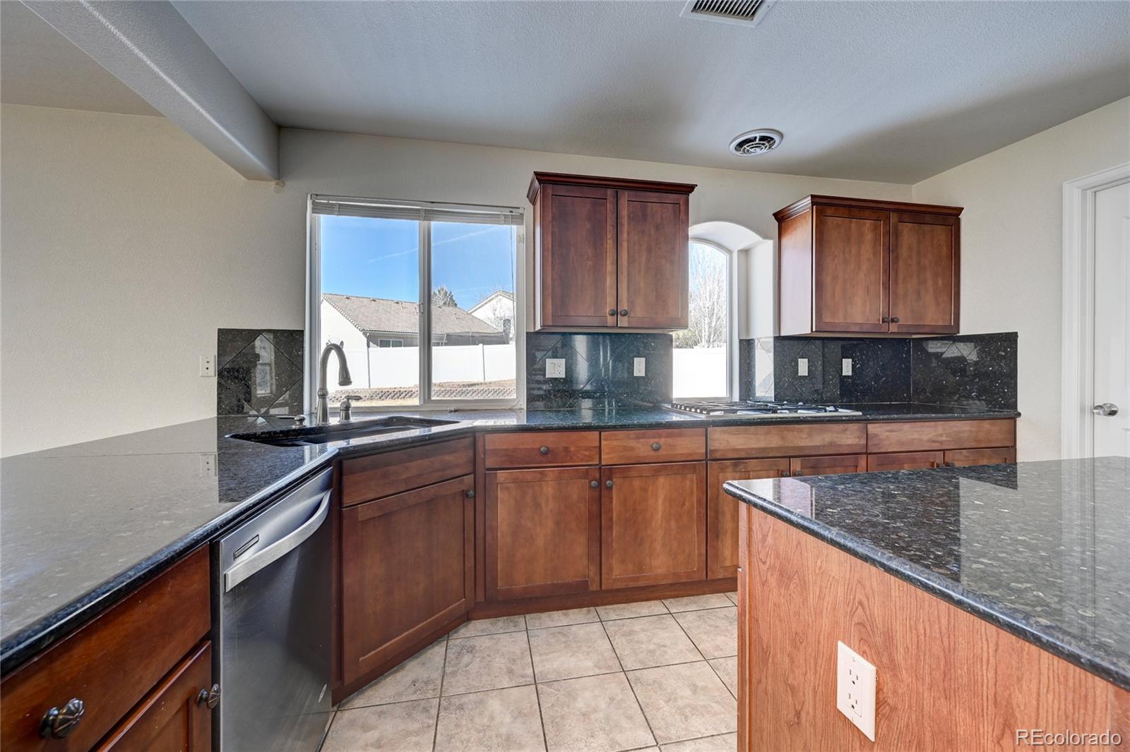 20527 Robins Drive Denver, CO 80249 - Photo 10 of 25 a kitchen with stainless steel appliances granite countertop a sink stove and microwave