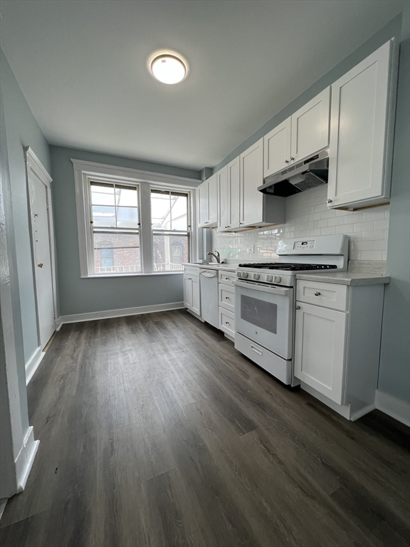 47 Hooker Street, Unit 3 Boston, MA 02134 - Photo 2 of 10 a kitchen with stainless steel appliances granite countertop a stove a sink dishwasher and white cabinets with wooden floor