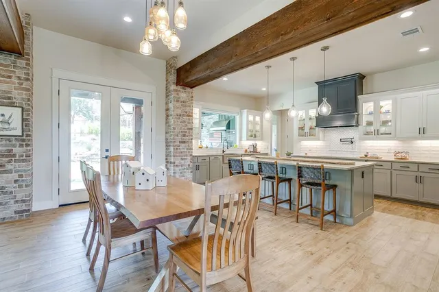 a dining room with stainless steel appliances kitchen island granite countertop a table chairs and a refrigerator