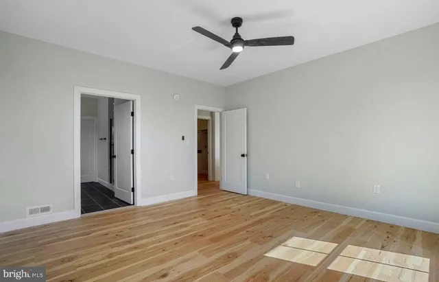 a view of a room with wooden floor and a ceiling fan