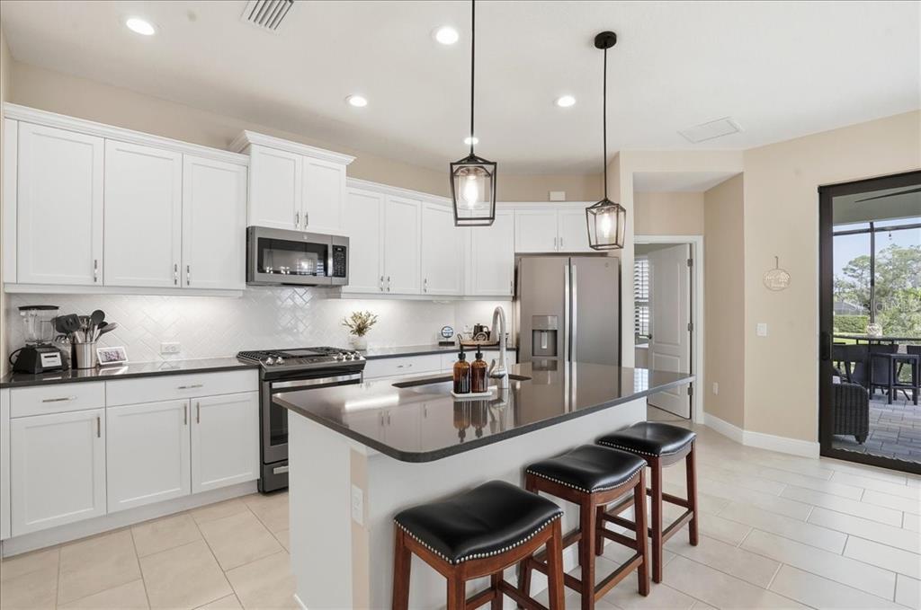 3511 Azurite Way Bradenton, FL 34211 - Photo 14 of 64 a kitchen with stainless steel appliances granite countertop a stove a sink a refrigerator a center island a stove and a cabinets