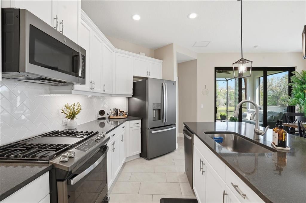 3511 Azurite Way Bradenton, FL 34211 - Photo 18 of 64 a kitchen with stainless steel appliances a sink a stove and microwave