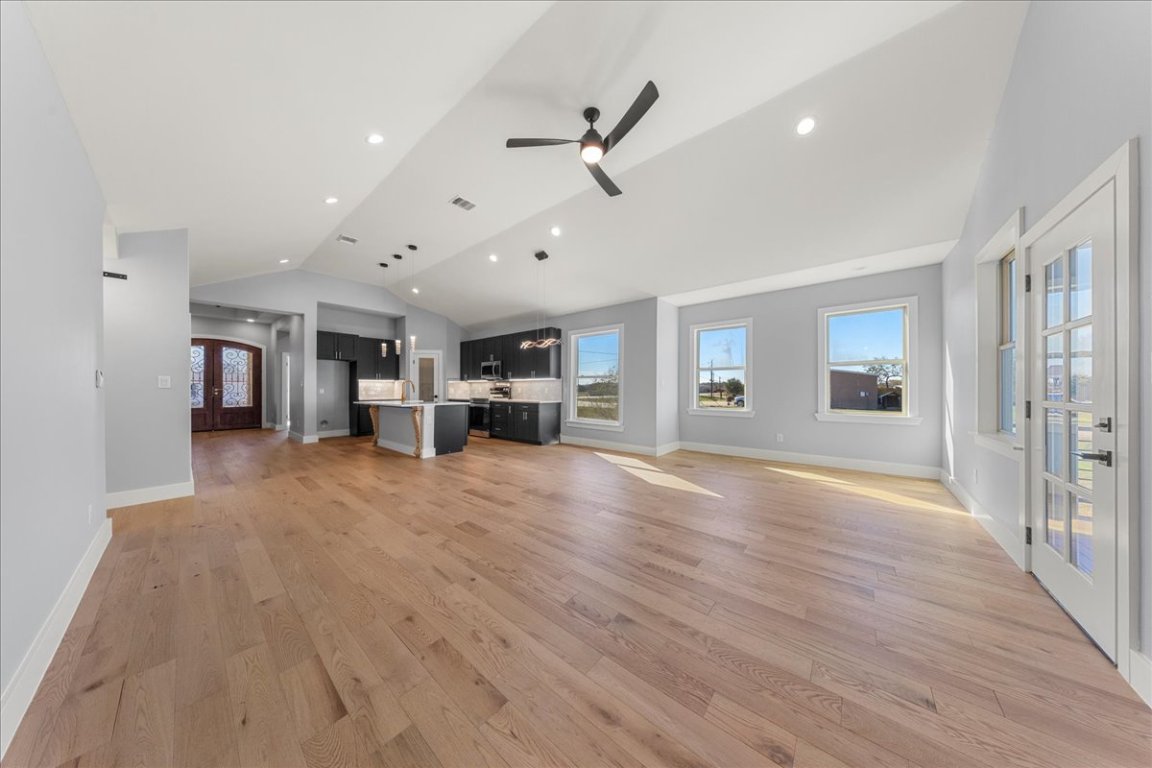 217 Gato Road Cedar Creek, TX 78612 - Photo 18 of 39 Unfurnished living room with french doors, lofted ceiling, light wood finished floors, recessed lighting, and a ceiling fan