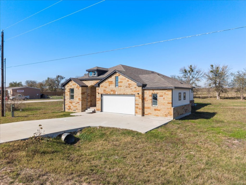 217 Gato Road Cedar Creek, TX 78612 - Photo 2 of 39 View of front facade with driveway, a front yard, a garage, and stone siding