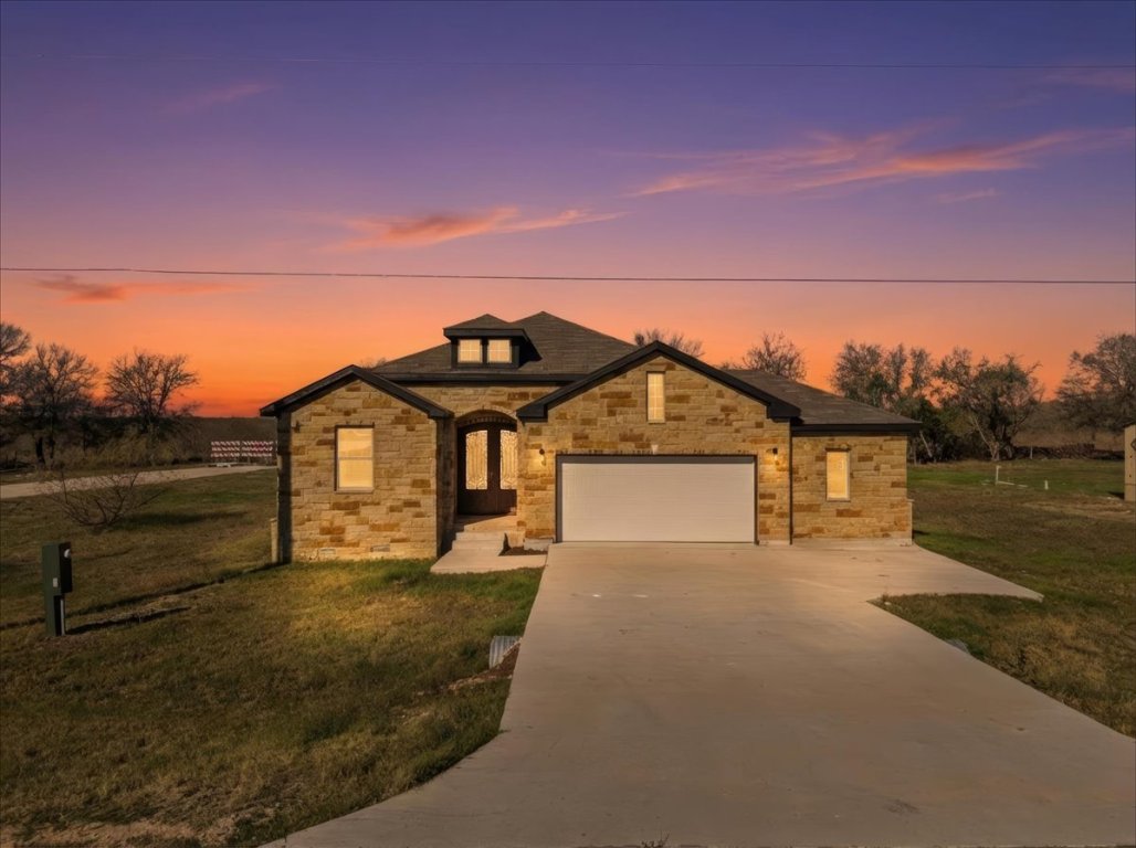 217 Gato Road Cedar Creek, TX 78612 - Photo 5 of 39 View of front of home with driveway, a front lawn, stone siding, and a garage