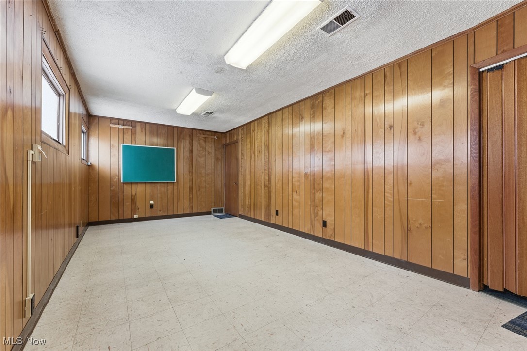 1817 Fulton Road Northwest Canton, OH 44709 - Photo 14 of 25 Spare room featuring light floors, wood walls, and a textured ceiling