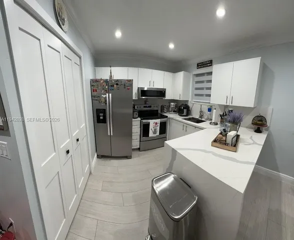 a kitchen with stainless steel appliances a refrigerator a sink a stove a microwave and island