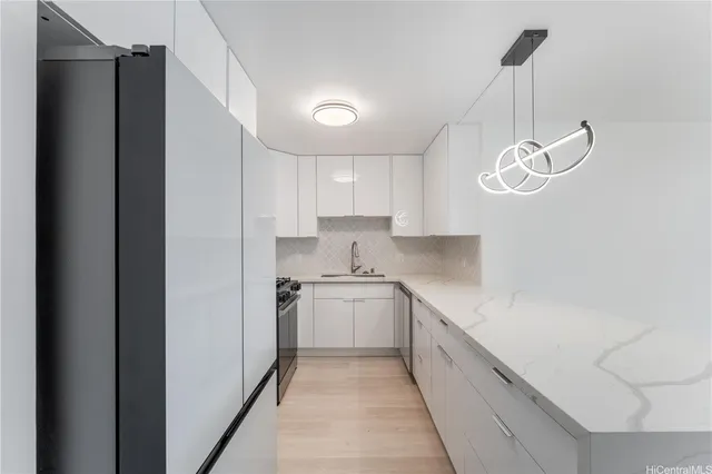 a kitchen with stainless steel appliances granite countertop a sink a stove a refrigerator and island with wooden floor