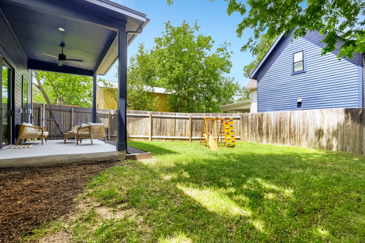 4804 Ribbecke Avenue, Unit A Austin, TX 78721 - Photo 25 of 32 The property features a covered patio with a ceiling fan, a spacious lawn area, and a wooden fence enclosing the backyard
