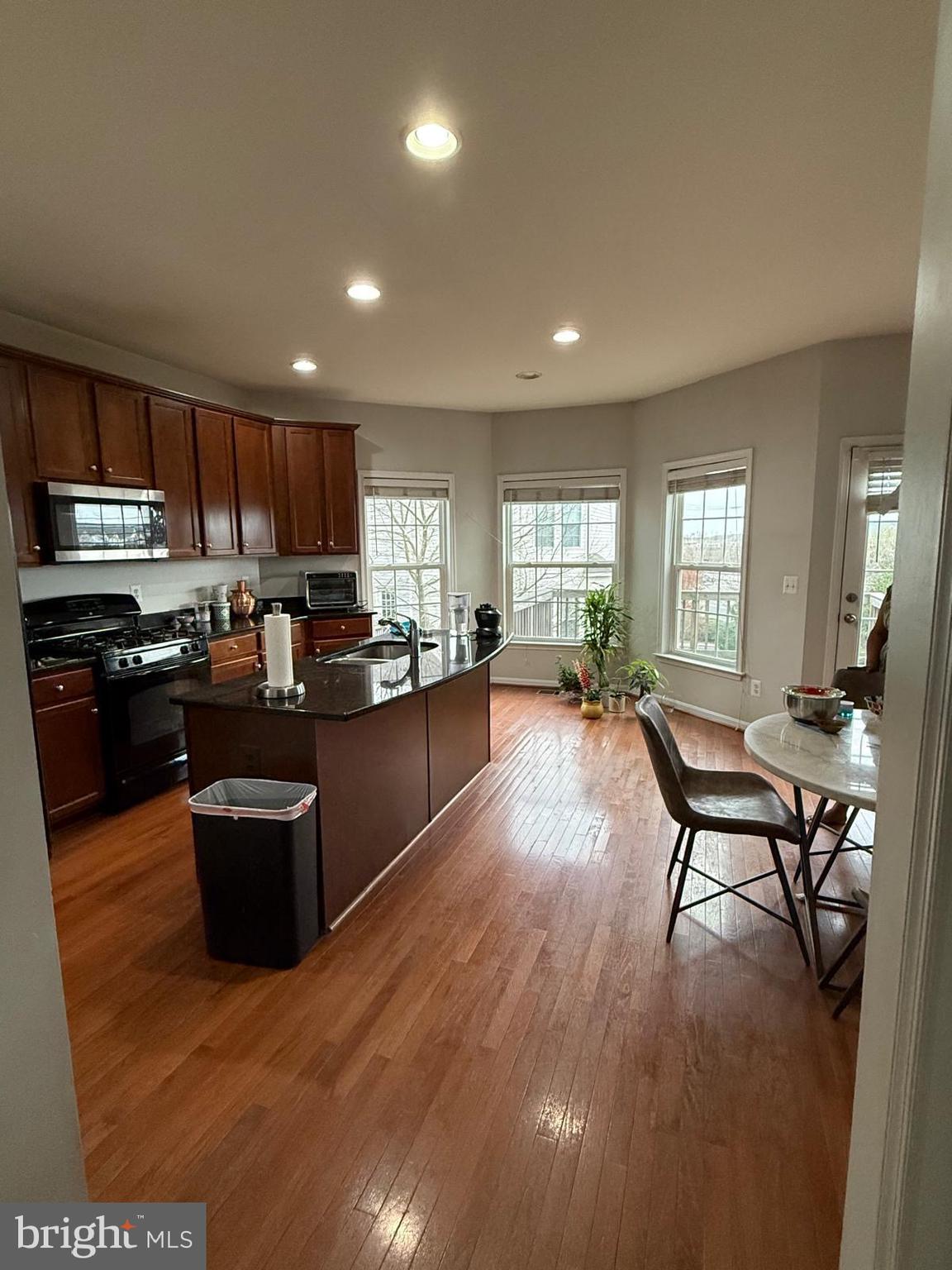 22573 Highcroft Terrace Brambleton, VA 20148 - Photo 2 of 13 a kitchen with stainless steel appliances granite countertop a stove top oven a sink dishwasher a dining table and chairs with wooden floor