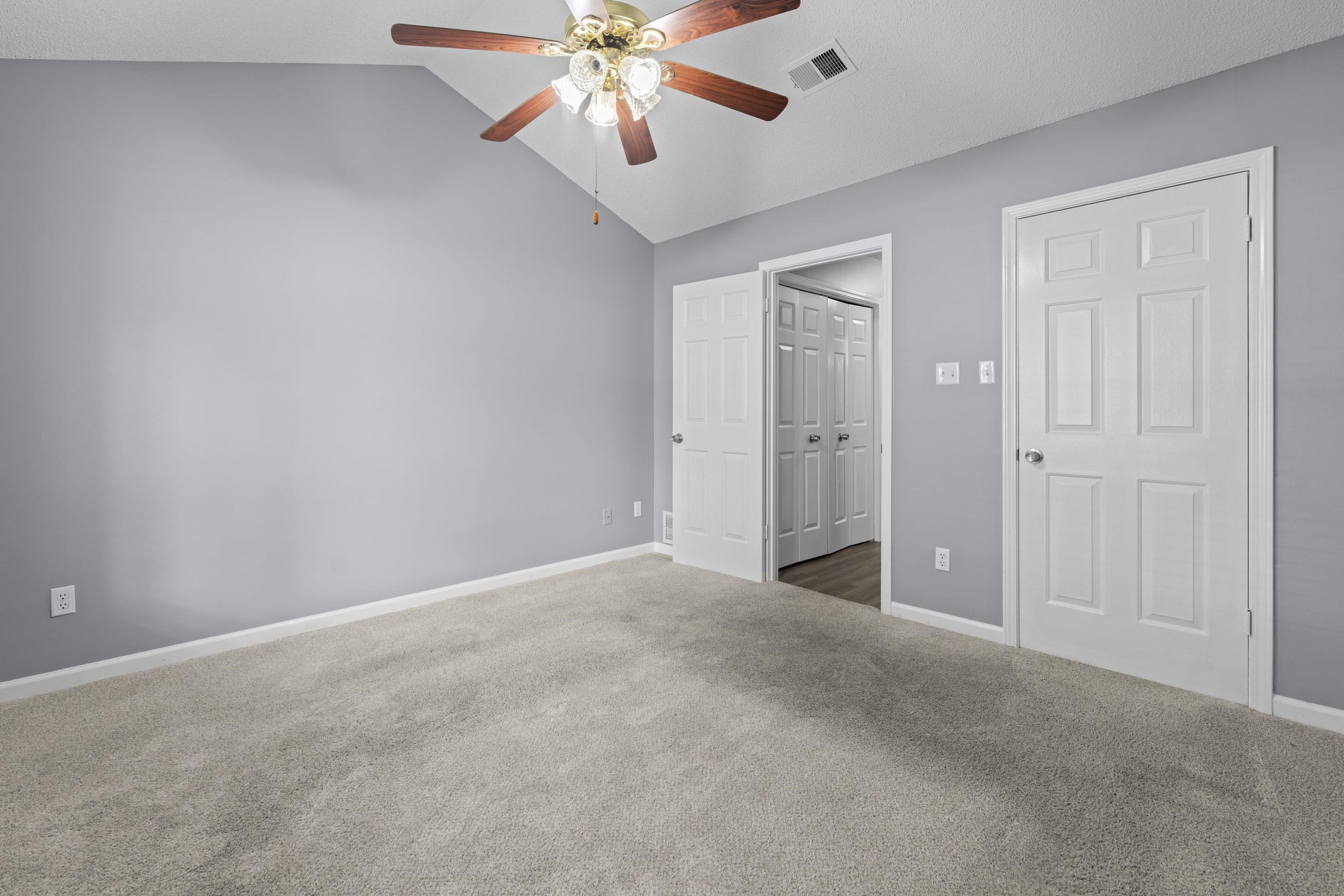 2252 Mangum Road Memphis, TN 38134 - Photo 16 of 23 Vaulted ceiling featuring a ceiling fan, light gray wall paint, light-colored carpeting, and white panel doors
