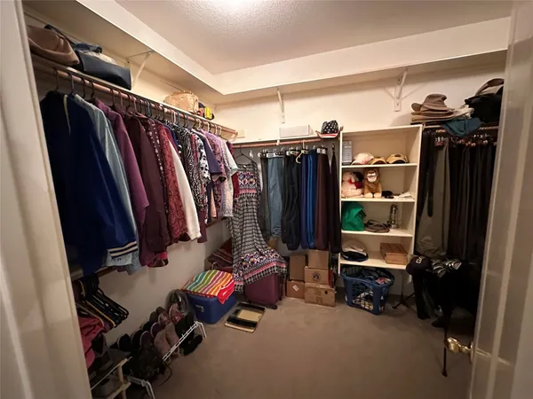 a view of walk in closet with clothes and shoes