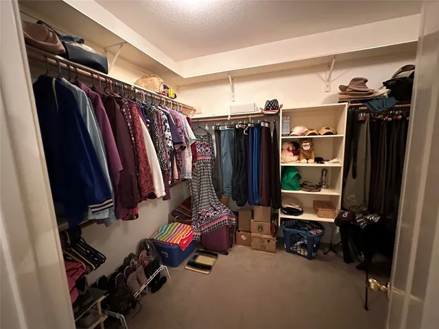 a view of walk in closet with clothes and shoes