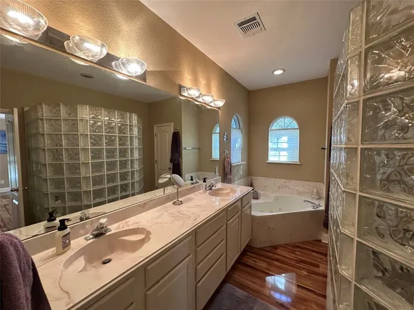 a spacious bathroom with a double vanity sink a large mirror and a bathtub