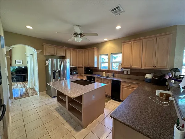 a large white kitchen with a stove a sink a counter top space and stainless steel appliances