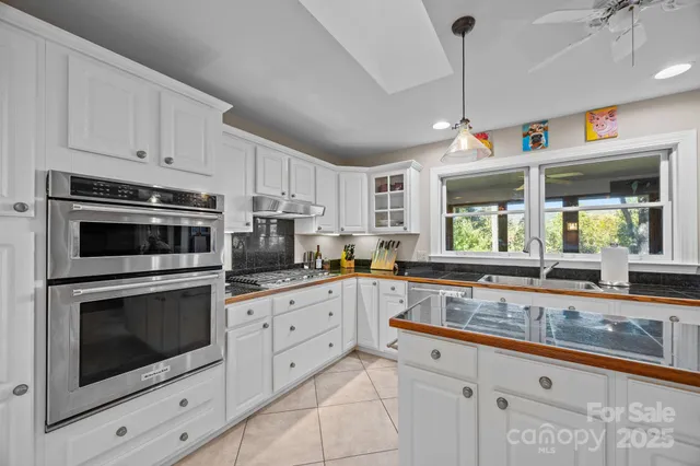 a kitchen with granite countertop a sink and a white wooden cabinets
