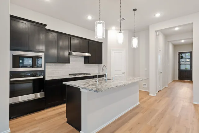 a large kitchen with a large counter top stainless steel appliances and wooden floor