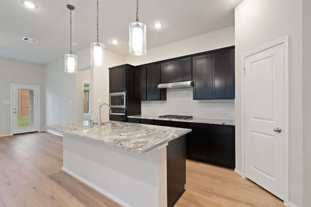 a large kitchen with a center island and stainless steel appliances