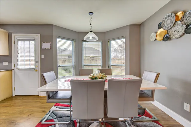 a kitchen with granite countertop a refrigerator a sink dishwasher a stove and white cabinets with wooden floor