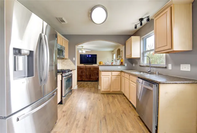 a kitchen with stainless steel appliances granite countertop a stove a sink and a window
