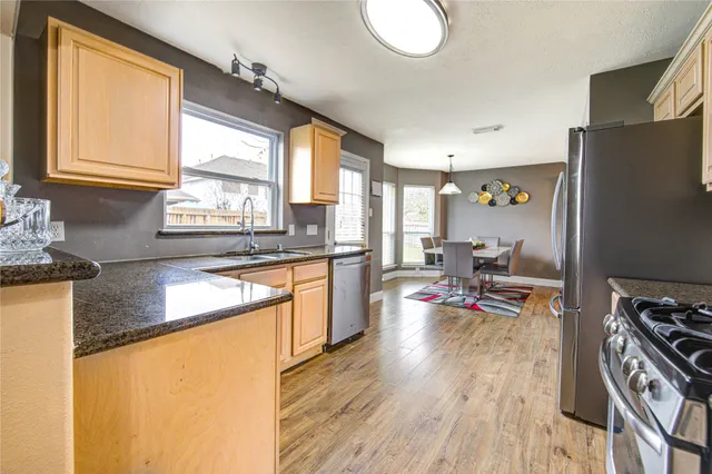a kitchen with stainless steel appliances granite countertop a stove a sink dishwasher and cabinets with wooden floor