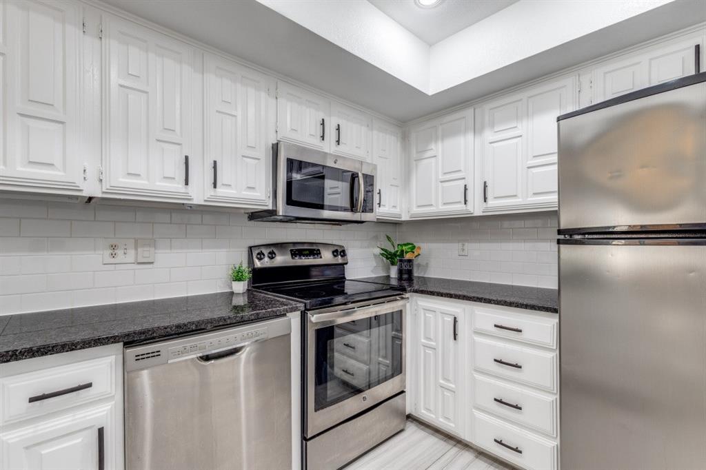 14151 Montfort Drive, Unit 345 Dallas, TX 75254 - Photo 13 of 31 a kitchen with granite countertop white cabinets stainless steel appliances and a sink