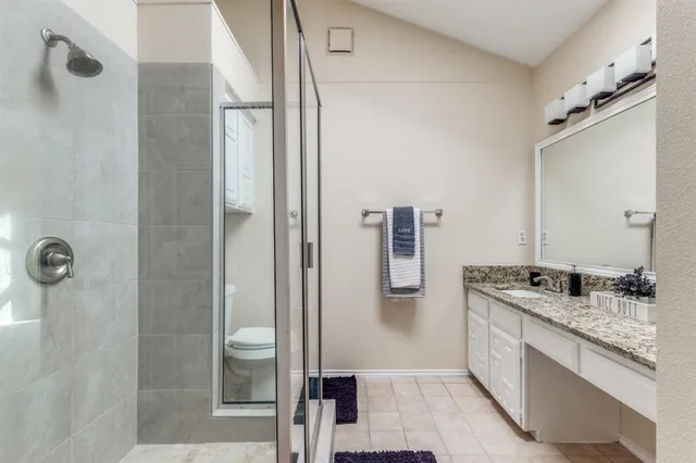a spacious bathroom with a granite countertop sink a mirror and shower